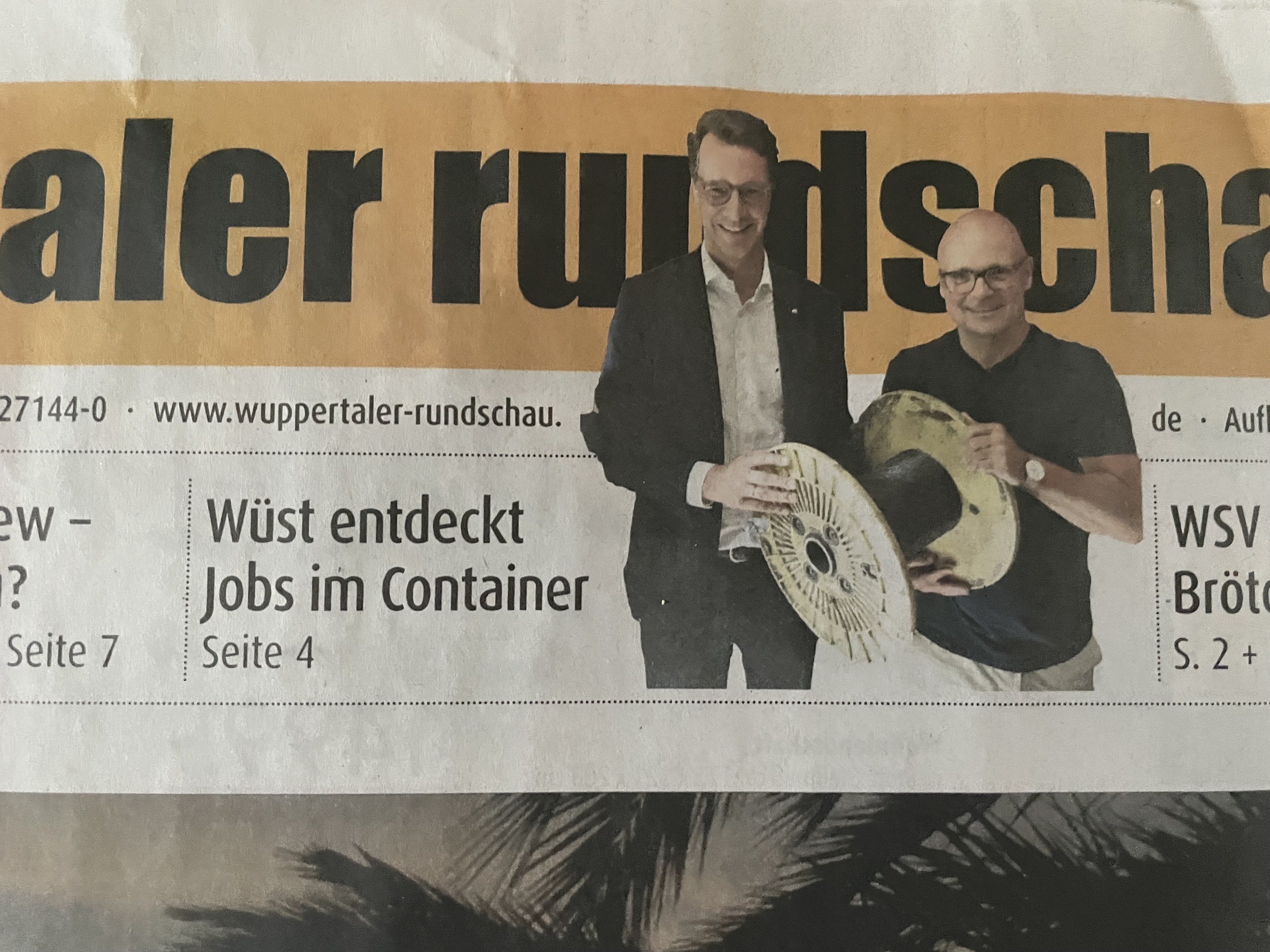 Ausschnitt des Titelblatts der Wuppertaler Rundschau mit der Schlagzeile „Wüst entdeckt Jobs im Container“. Daneben ein Freisteller von Ministerpräsident Wüst grinsend mit einer kleinen Kabeltrommel. 